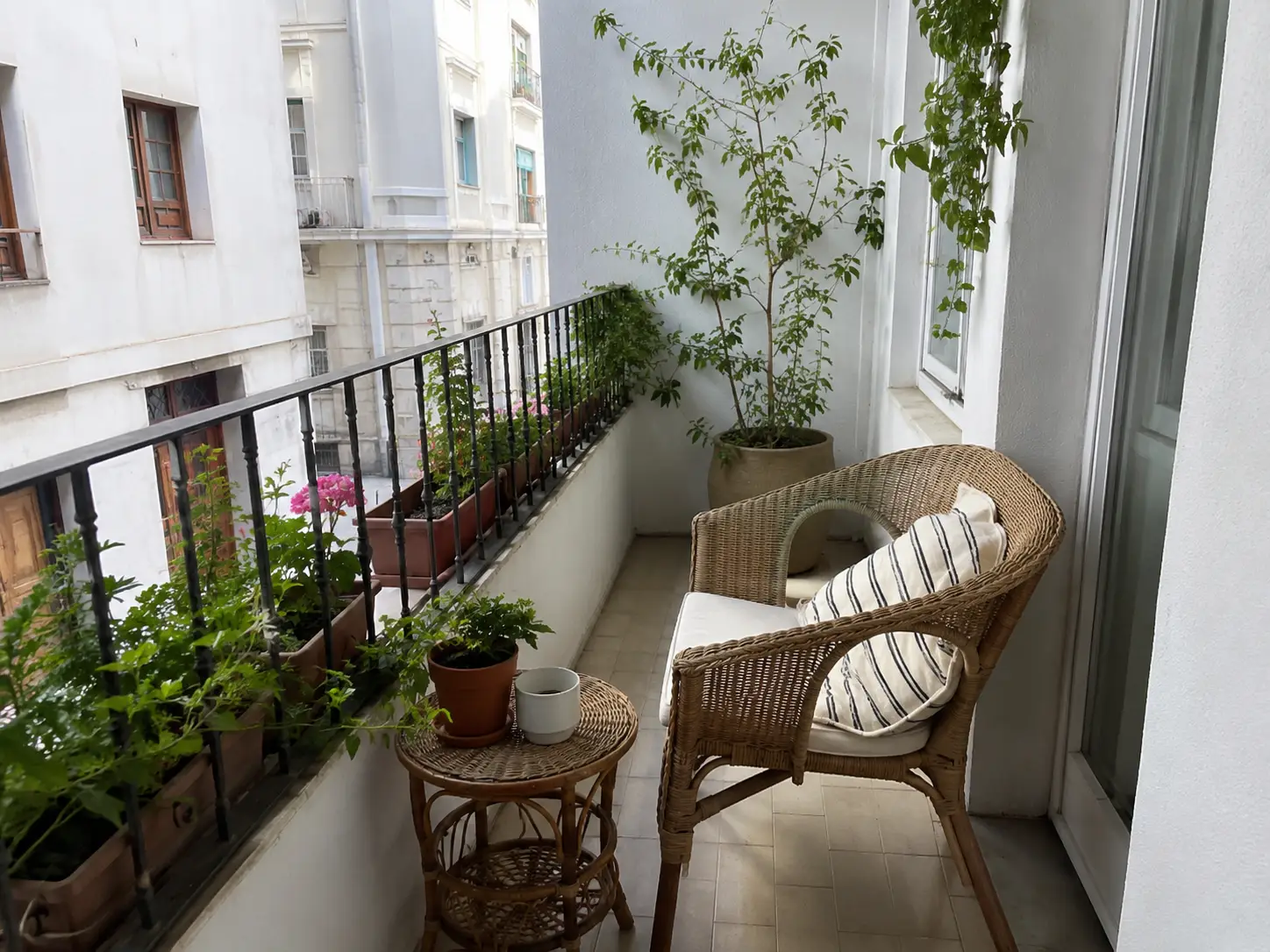 Balcón pequeño con muebles de mimbre y plantas